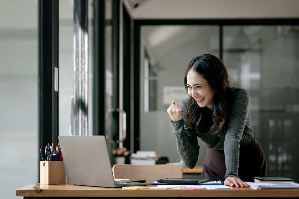 Beautiful Asian woman celebrate with laptop, successful business startup small business concept.